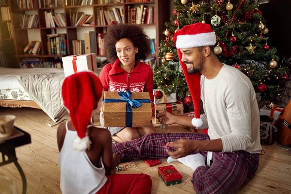 在装饰圣诞树前交换礼物的家庭 — 图库照片