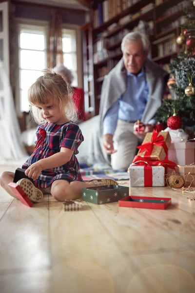 可爱的女孩是打开圣诞礼物前装饰的圣诞树 — 图库照片#