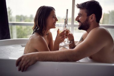 Romantik Genç çift zevk ve banyoda rahatlatıcı ve şampanya içmek
