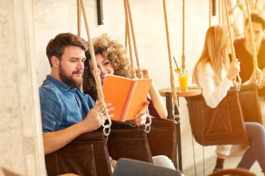 Genç Çift salıncak içinde kitap okumak