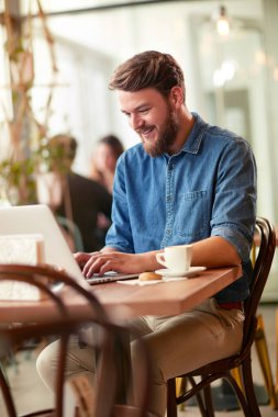 Dizüstü bilgisayarda çalışan neşeli adam