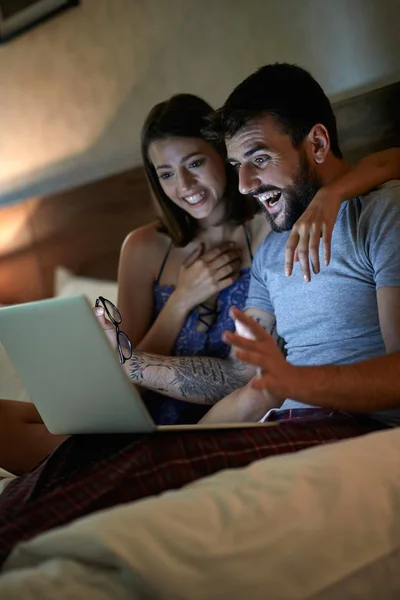 幸せな男と女が自宅のベッドでリラックス楽しく映画を見てください — ストック写真