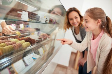 Kız bir Pastane annesi ile vitrin macarons seçin 