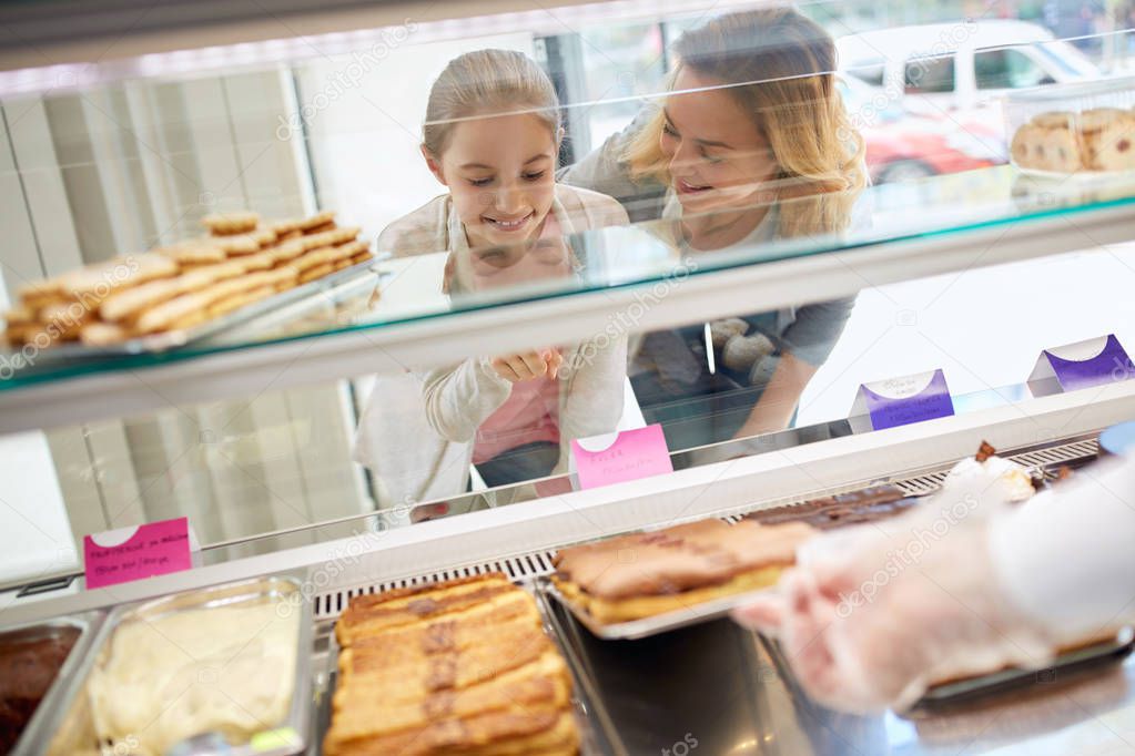 Young girl with mother look at cookies in pastry shop