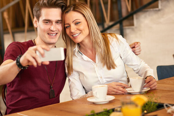 Male and female making selfie together in restaurant