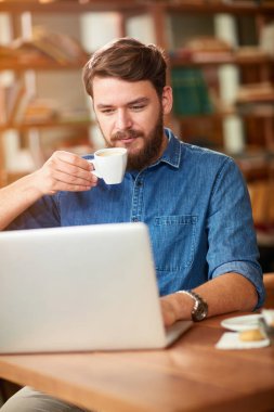 Genç adam içecekler kahve ve laptop kafede çalışmak