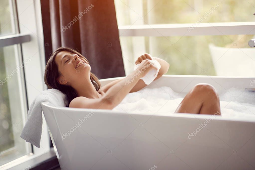 Beautiful smiling woman relaxing in bath with foam