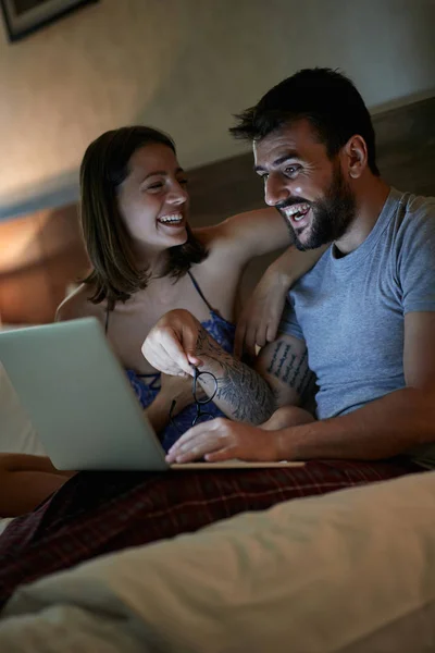 Pareja divirtiéndose relajándose en la cama en casa en la noche disfrutando — Foto de Stock