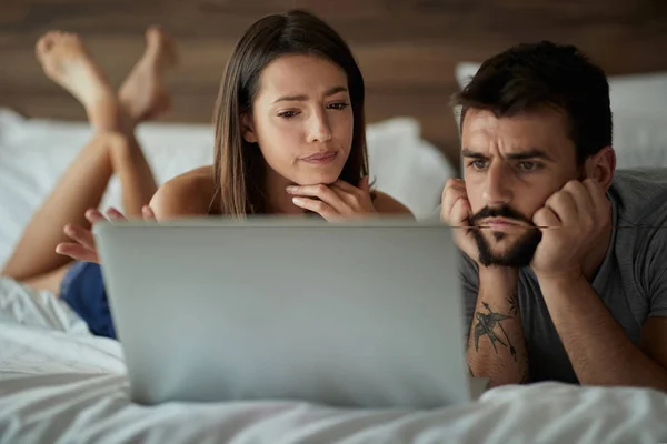 Vriend en vriendin ontspannen in bed met laptop liggen samen — Stockfoto