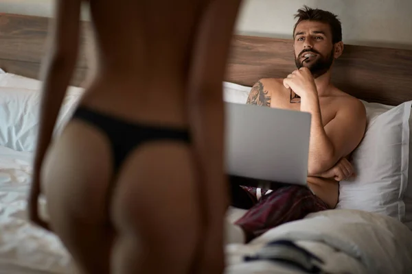 Seksi aşık tutku içinde-adam yatakta yatarken ve kadın iç çamaşırı arıyor — Stok fotoğraf