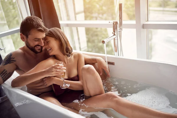 Sonriente pareja bebiendo champán y bañándose juntos — Foto de Stock