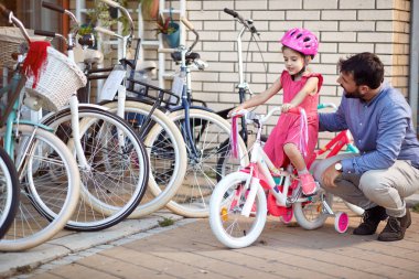 Young father buying new bicycle for little girl in bike shop clipart