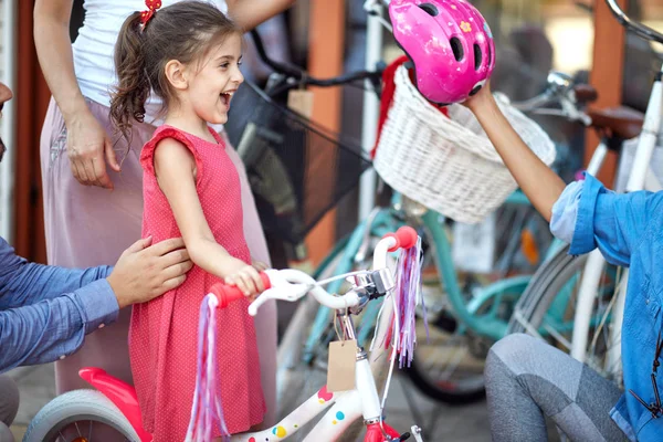 在自行车商店为女孩买自行车头盔的家庭 — 图库照片