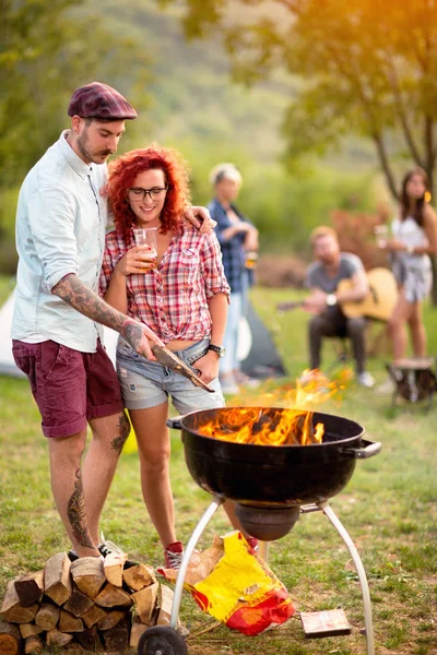 Curly Ingefær jente med tatovert fyr se på grill ild – stockfoto