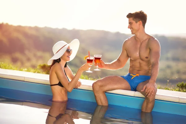 Pareja feliz en el lado de la piscina con cócteles — Foto de Stock