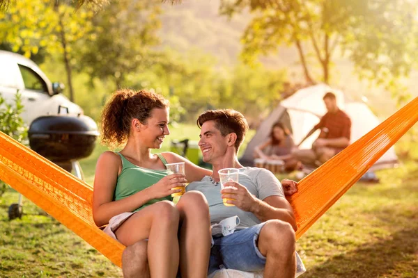 Smilende par nyder i hængekøje stol på camping tur - Stock-foto