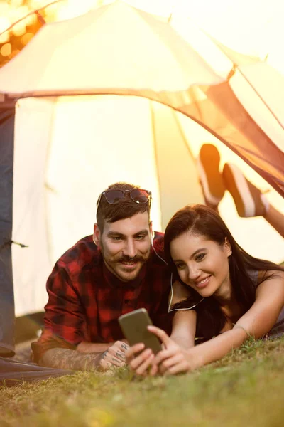 Casal deitado na tenda e tomando selfie — Fotografia de Stock