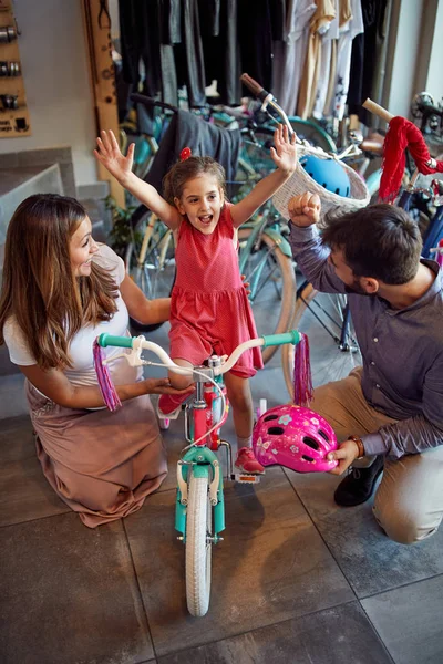 年轻的父亲和母亲为双性恋的小女孩选择新自行车 — 图库照片
