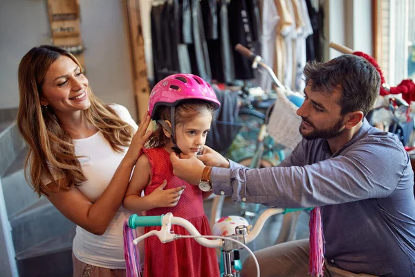 Joven familia elección nueva bicicleta para niña en la tienda de bicicletas —  Fotos de Stock