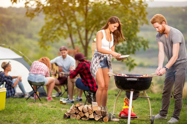 Brunette meisje met vriendje zetten vlees van de grill in grill — Stockfoto