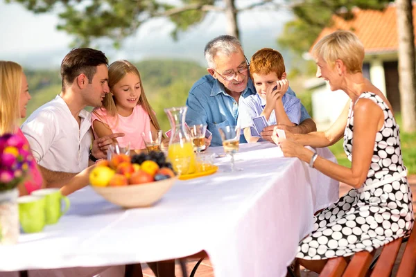 Щаслива сім'я сидить за столом на відкритому повітрі — стокове фото