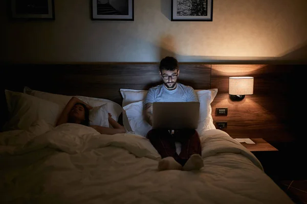 Ágyon, és dolgozik a laptop késő este fáradt üzletember — Stock Fotó