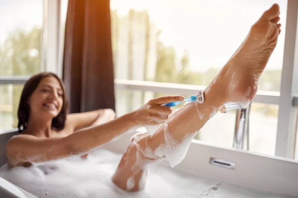 Giovane donna che si depila le gambe nel bagno — Foto Stock