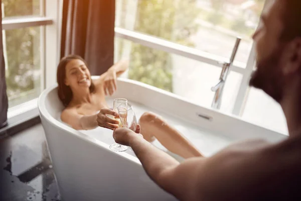 Jóvenes hombres y mujeres disfrutan el uno del otro en el baño y beber champán —  Fotos de Stock