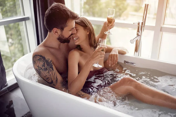 Hermosa pareja bebiendo champán en la bañera —  Fotos de Stock