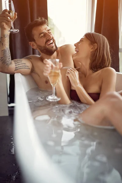 Casal relaxante em banho de bolha e beber champanhe — Fotografia de Stock