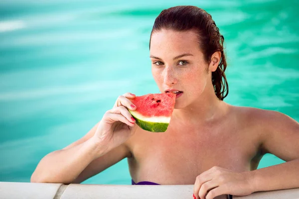 Donna seducente in piscina rinfresca con pezzo di anguria — Foto Stock