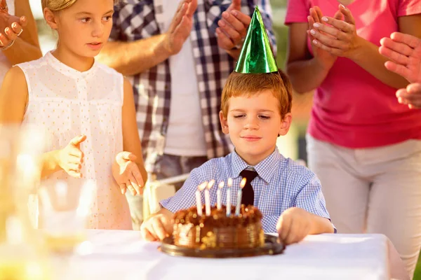 Мальчик с праздничной шапкой и тортом на день рождения — стоковое фото