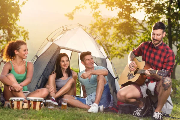 Unge mennesker nyder i musik på camping tur - Stock-foto