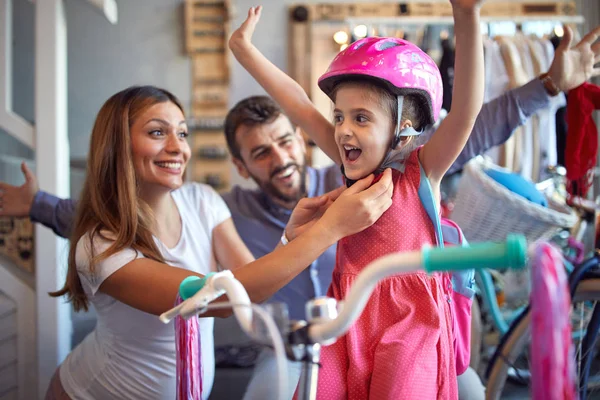 Жінка купує новий велосипед і шолом для маленької дівчинки в велосипедному магазині — стокове фото