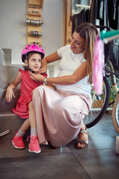 Hermosa madre embarazada a la compra de casco nuevo para su chica en —  Fotos de Stock