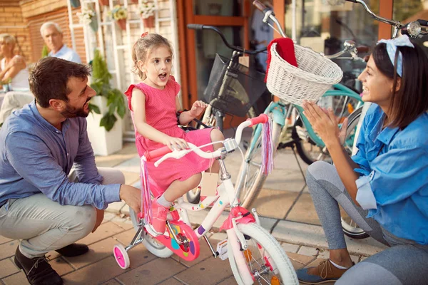 年轻的父亲在自行车车里给女儿买了新自行车 — 图库照片