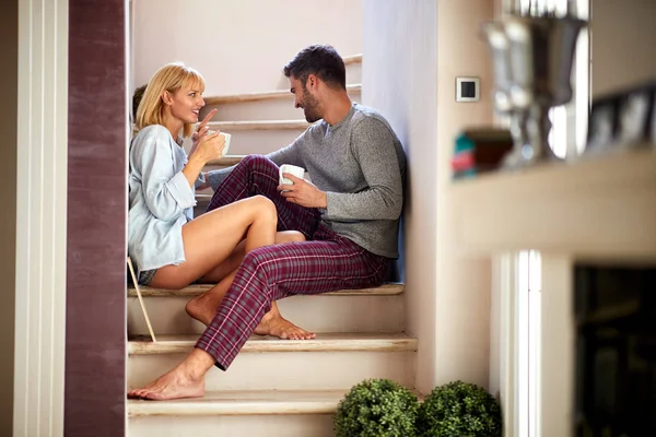 Couple sitting on stairs and drinking coffee — Stock Photo, Image