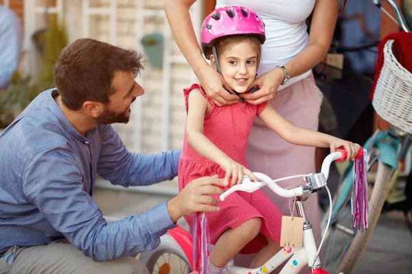 母亲买在快乐的女孩自行车头盔在自行车店 — 图库照片