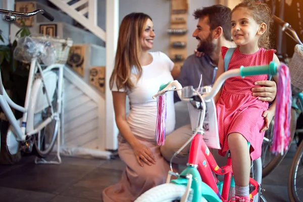cheerful family buying new bicycle for little girl in bike shop
