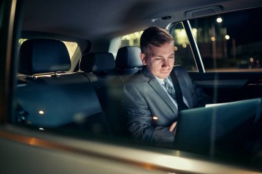 Otomobilin arka koltuğunda dizüstü bilgisayarı üzerinde çalışan iş adamı odaklanma