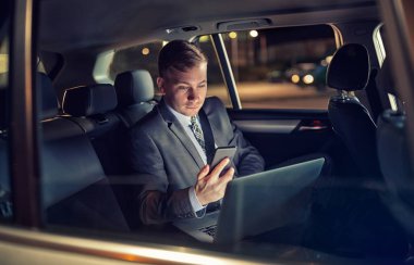 Otomobili gezerken cep telefonunu kullanan işadamı