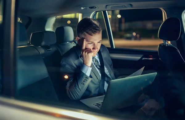 Businessman in moving car working on his laptop — Stock Photo, Image