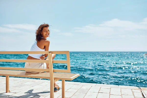 Menina bonita viajante sentado no banco perto da praia — Fotografia de Stock