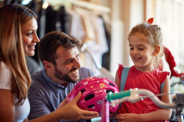 Sorrindo pai e mãe comprando nova bicicleta para a menina na loja de bicicletas — Fotografia de Stock