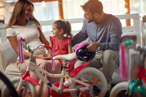 Jovem pai e mãe comprando nova bicicleta para criança na loja de bicicletas — Fotografia de Stock