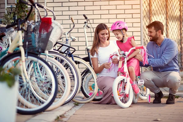 Família com filha se divertindo ao ar livre compras nova bicicleta em — Fotografia de Stock