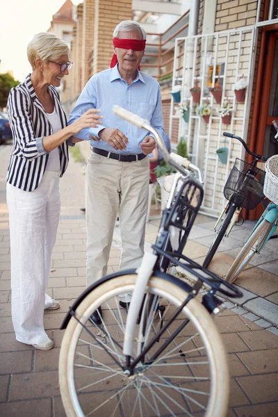 Женщина закрывает глаза мужчины для сюрприза с покупкой подарочного велосипеда — стоковое фото