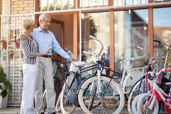 Femme âgée souriante et homme achetant un nouveau vélo dans le magasin — Photo
