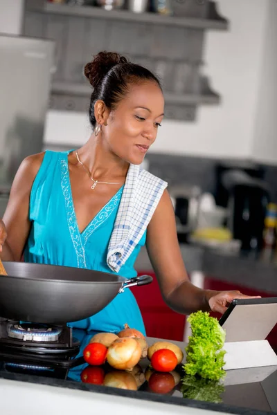 Mujer preparando comida y mirando la tableta —  Fotos de Stock