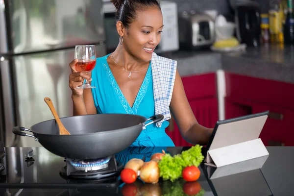 Frau schaut beim Zubereiten von Essen auf digitales Tablet — Stockfoto